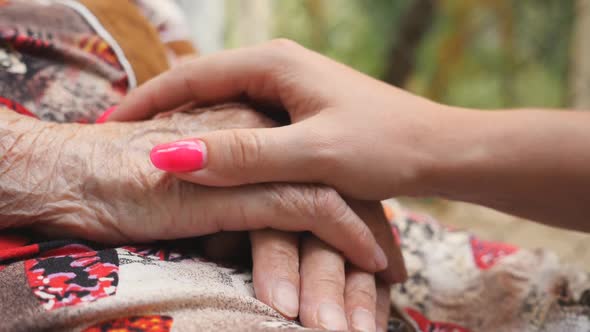 Close Up of Young Female Arm Stroking an Elderly Hands of Old Woman. Granddaughter and Grandmother