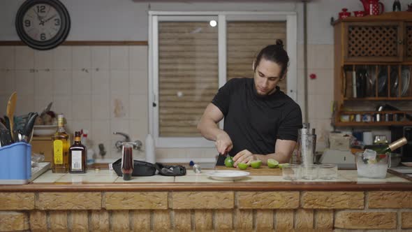 Attractive Young Bartender Slicing Limes for Cocktail Preparation in a Traditional Spanish House