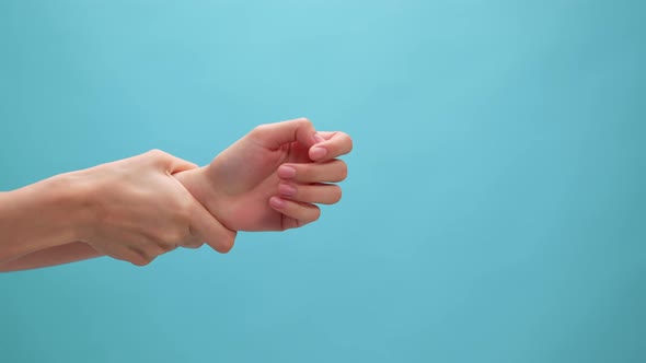 Close up shot of woman hand touching wrist and stretch joint on the blue background