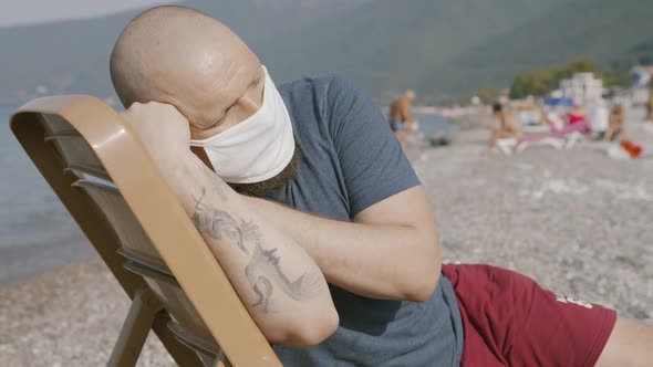 Young Caucasian Man Sleeping at Beach Deck Chair with Medical Mask Tired of Coronavirus Pandemic