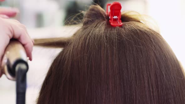 Hands Straighten Hair with Tongs Girl in a Beauty Salon