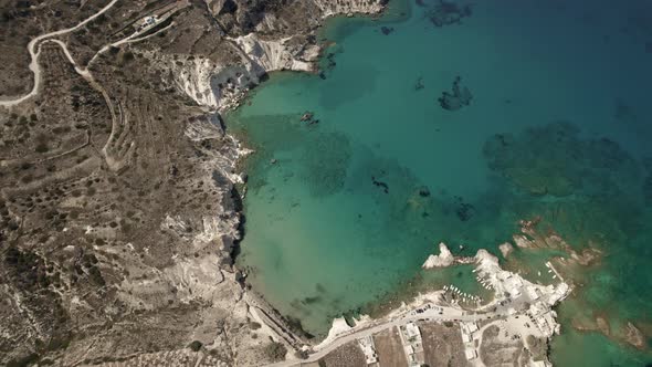 Transparent vibrant blue waters surround a holiday beach town on the Mediterranean. Summertime Milos