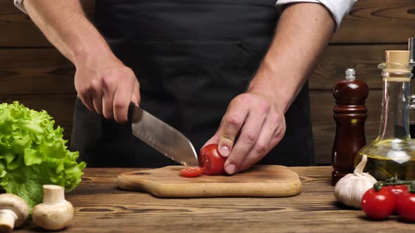 Male Hands Using a Kitchen Knife Cut Fresh Tomatoes on a Wooden Cutting Board