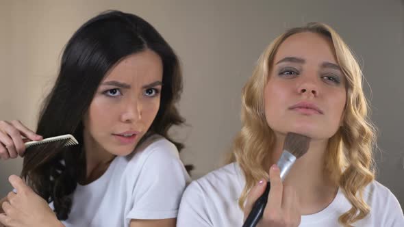 Two Girls Applying Make Up Fighting for Place in Front of Mirror