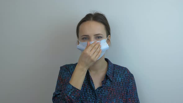 Young woman in protective medical mask is sneezing. Female wearing face mask is coughing.