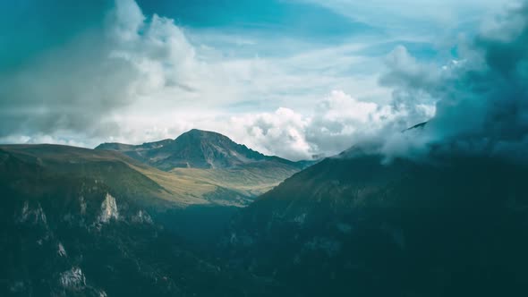 A mountain gorge covered with a forest. In the background rises a mountain with a glacier