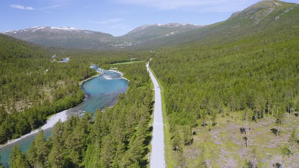 Asphalt Road Near The Strynselva River Surrounded With Green Forest In Stryn, Norway. aerial