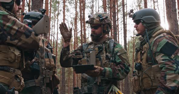 A Group of Middleaged Bearded Soldiers in Uniforms and Tactical Vests Discusses the Action Plan and