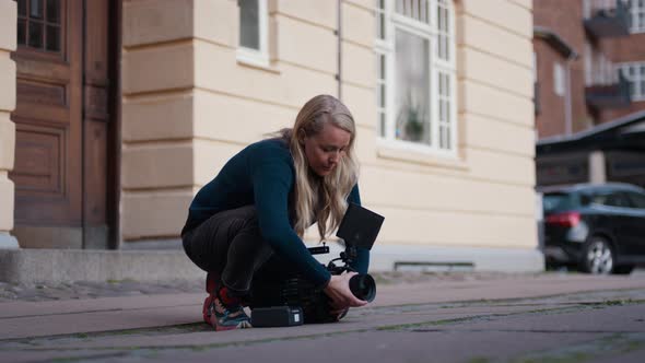 Female Film Maker Kneeling On Pavement To Fit Lens