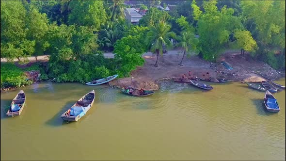 Flycam Moves Closely To River Bank with Fishing Boats By Road