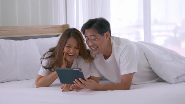 Happy senior couple using tablet computer together on the bed
