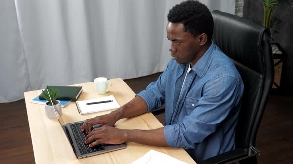 African American Man Works for Laptop Typing on the Keyboard in Office