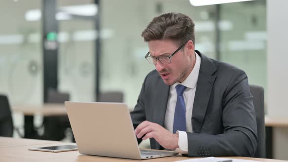 Loss, Middle Aged Businessman Reacting To Failure on Laptop in Office 