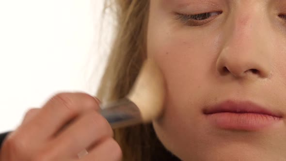 Makeup Artist Applying Shimmer Powder on Beauty Woman Face. Close Up. Slow Motion