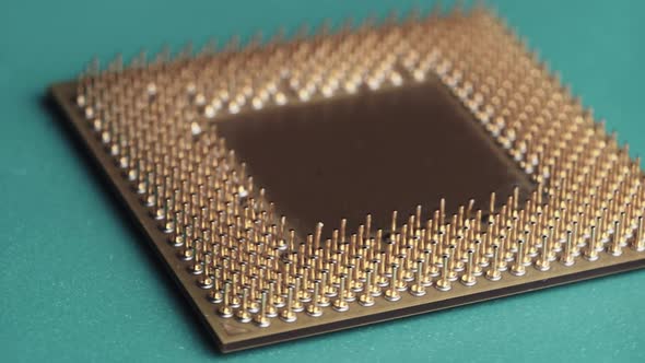 The Computer Processor CPU with Gold Plated Contacts Spins on Green Background