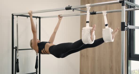 Beautiful Woman Doing Pilates Exercise on Machine