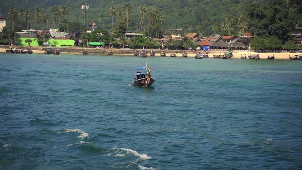 Boat Sailing Out By the Koh Phiphi Beach with a View of Coconut Trees and Mount