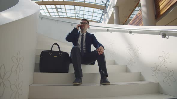 Successful Confident Businessman Sitting on Stairs Talking on Cell Mobile Phone