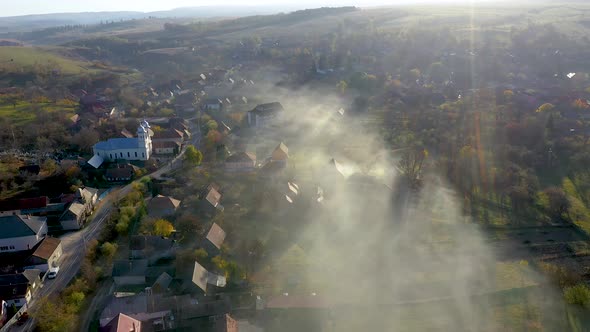 Flying Above a Village Covered in Morning Haze and Mist