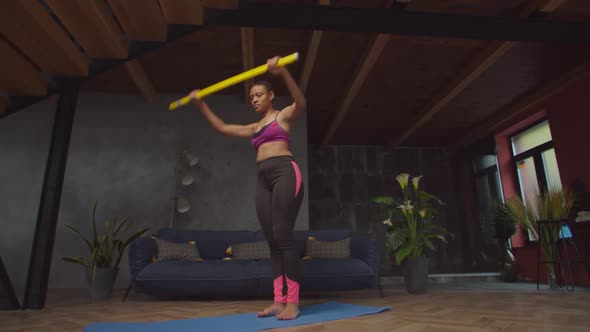 Fit Female Exercising Glute Kickback with Bar