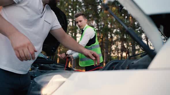 Two Man Charging Car Battery with Electricity Trough Jumper Cables