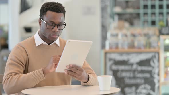 Attractive Creative African Man Using Tablet in Cafe