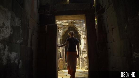 Following Back of Woman Walk Through an Ancient Doorway in Angkor Wat