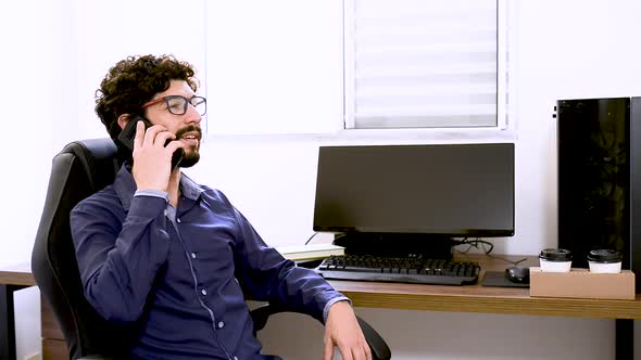 Latin man having a conversation at phone in office. Steady shoting. Home office subject.