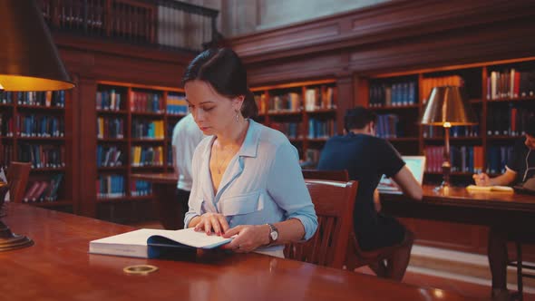 Young woman reading a book in the library of New York City