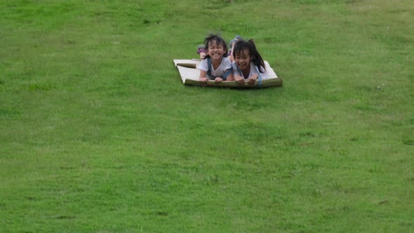 Two smiling little sisters lie prone on cardboard boxes sliding down