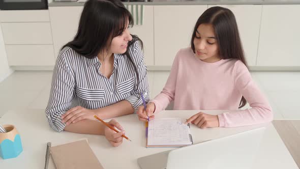 Young Indian Mom and Schoolgirl Doing Home Work Online Together at Home