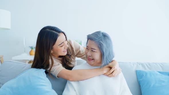 Portrait of Asian lovely family, young daughter hugging senior older mother and looking at camera.