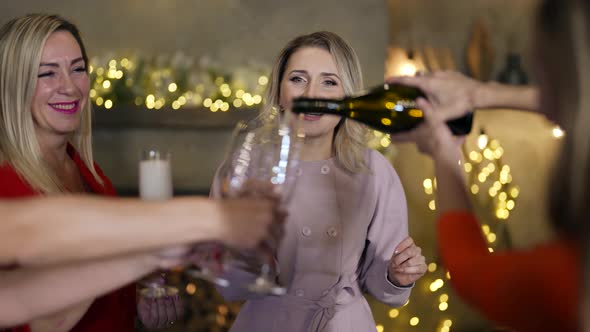 a Woman Pours Sparkling Wine Into Girlfriends' Glasses