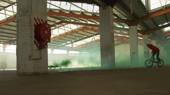 BMX riders in an empty warehouse using smoke grenade