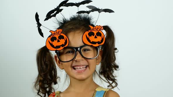 A little girl in a Halloween outfit laughs cheerfully and enjoys the holiday.