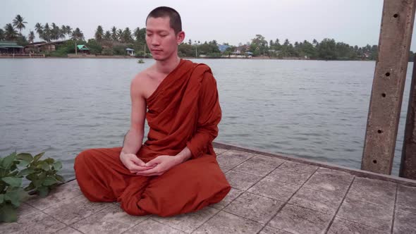 Monks were meditating at the waterfront near the Bodhi tree. Slow motion.