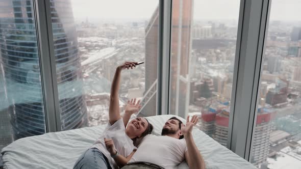 An Authentic Shot of a Happy Couple Taking a Selfie or Video Call in Bed in a Modern Apartment