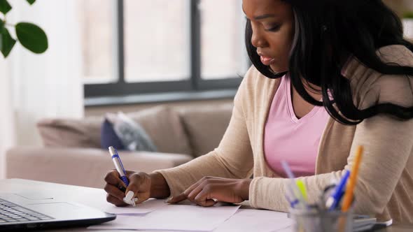 Woman with Calculator and Papers Working at Home