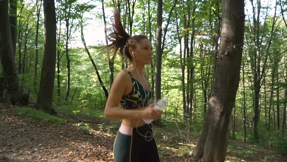 Slow Motion Footage of Brunette Fitness Girl in Sportswear with Earphones Jogging