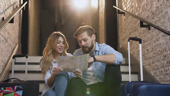 Cheerful 30s Pair in Love which Sitting on Stairs and Using Map Talking