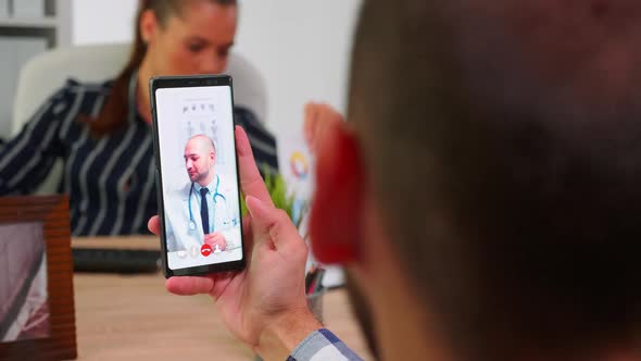 Businessman Talking on Video Call with Doctor in Work Time