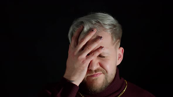 Disappointed Man Doing Face Palm Gesture on Black Background