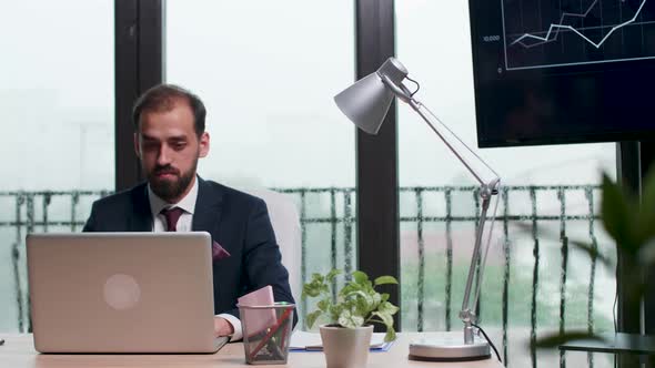 Businessman in Formal Suit Typing on Laptop