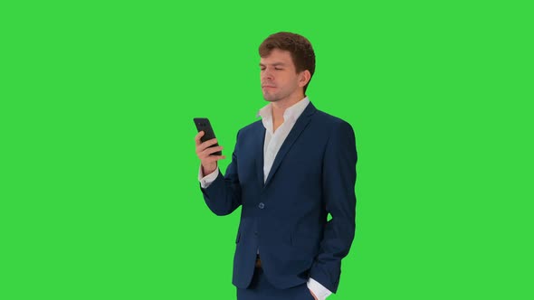 Serious Businessman Looking at His Phone on a Green Screen, Chroma Key