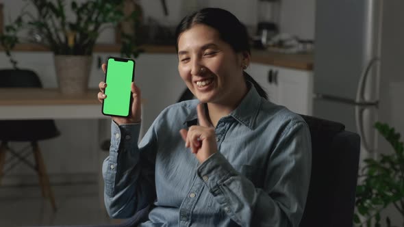 Asian Young Woman Smiling Holding a smartphone With Green Screens, Showing a New App