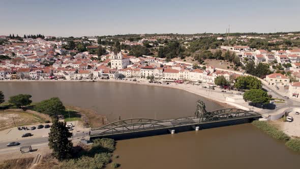 Alcacer do Sal bridge over Sado river and riverside cityscape. Aerial view