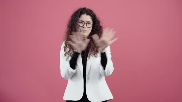 Exhausted Young Woman with Curly Hair Shows the Stop Sign with Her Palms Looking Into the Room