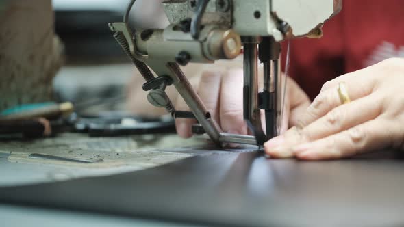 Close-Up Of Tailor Working On Sewing Machine in leather factory background