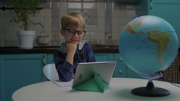 Happy School Kid Showing Thumb Up Looking at Camera Using Tablet Computer at Home