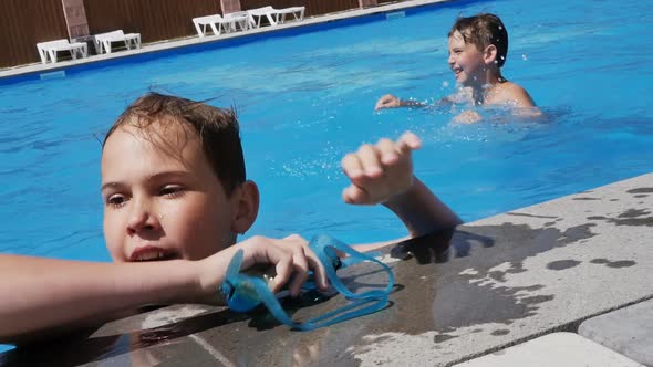 Two Teenagers are Swimming in a Beautiful Blue Pool Using Water Goggles and a Ball